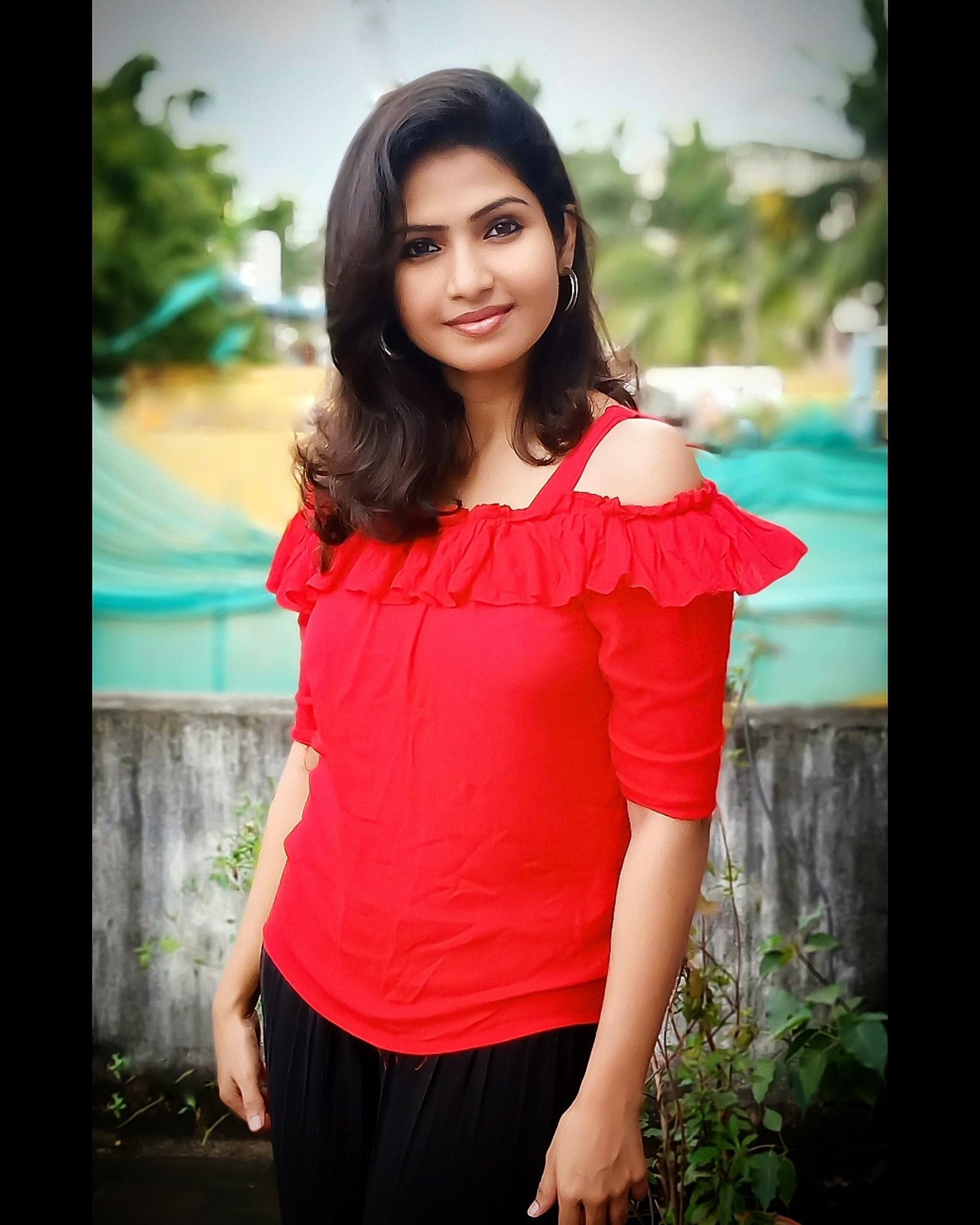 Venba stands outdoors in a richly colored garment, adorned with gold jewelry and framed by warm lighting.