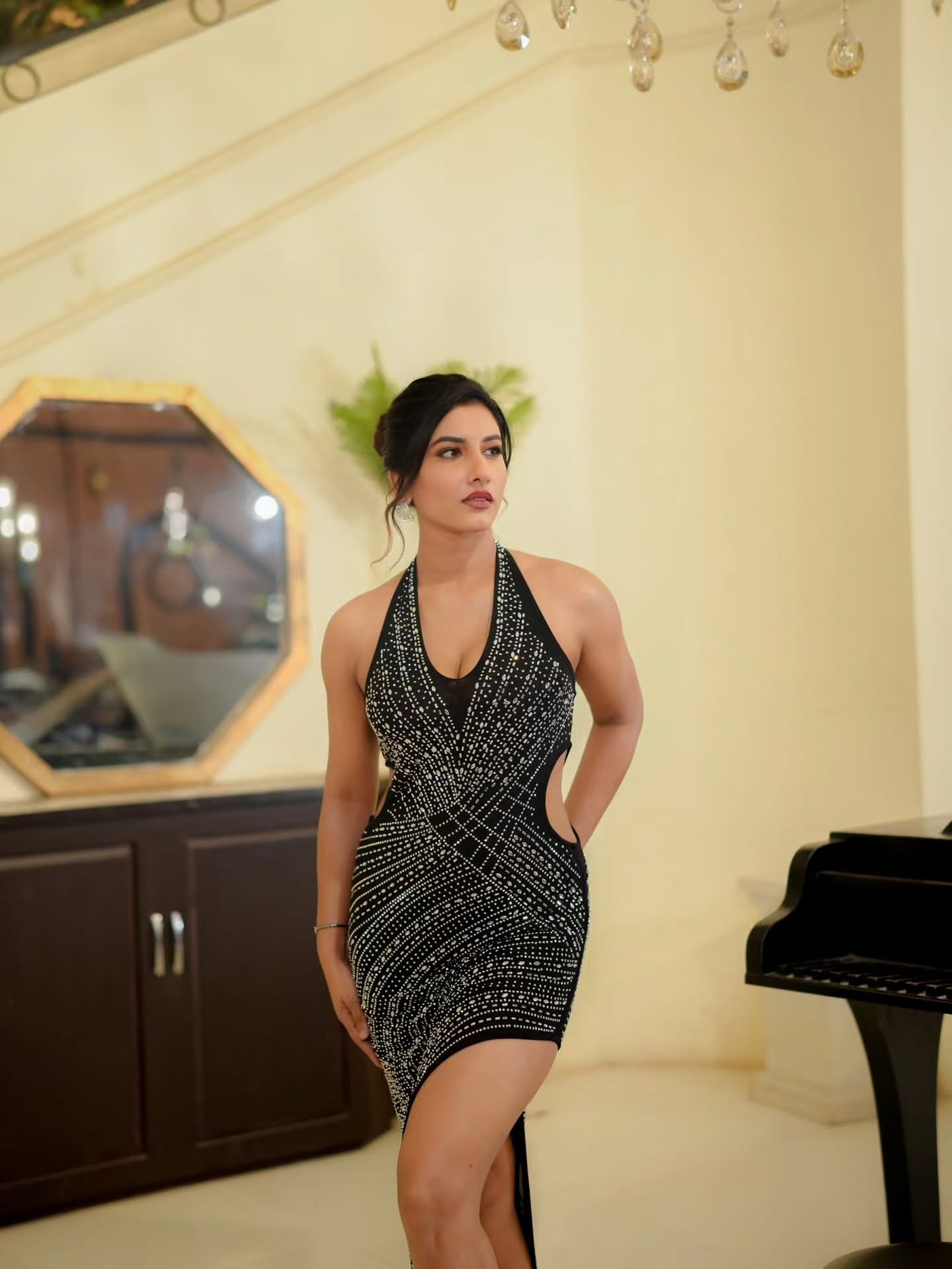 Vishnu Priya Bhimeneni stands poised in a stunning, heavily beaded black sleeveless evening gown indoors.