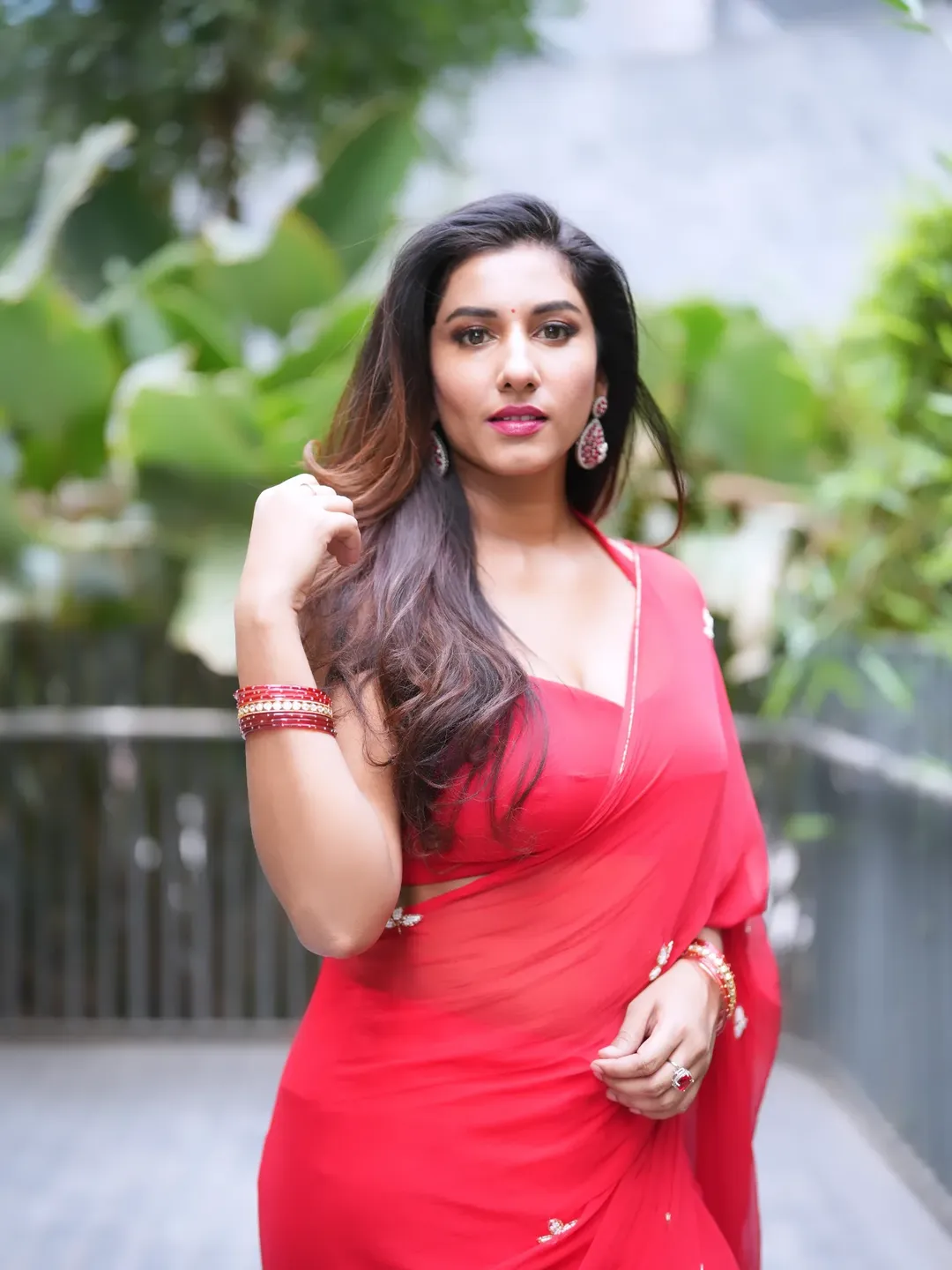 Vishnupriya Bhimeneni wearing a flowing red saree with sheer fabric and subtle motifs outdoors.
