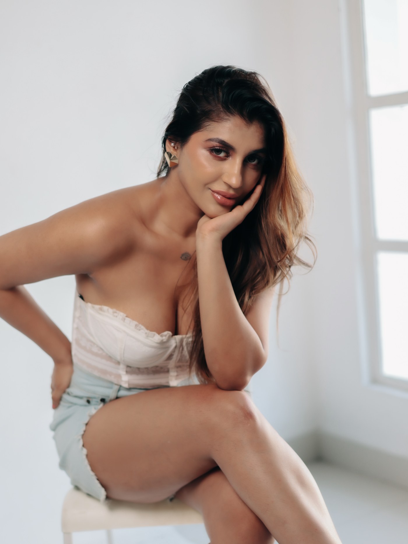 Yashika Aannand radiates confidence in a bold white lace top paired with light wash denim shorts.